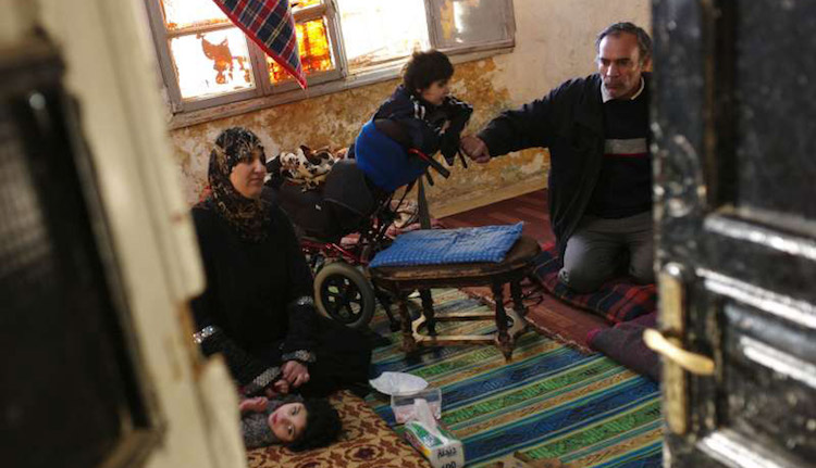 Photo: Members of a family gather on the floor of their dilapidated apartment in downtown Amman, Jordan. Photo: UNHCR/B. Szandelszky