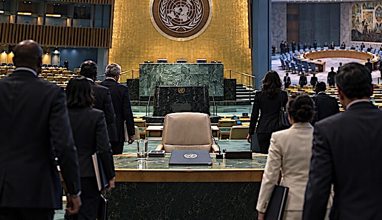 Diplomats approach an empty chair in the UN General Assembly Hall, symbolising the unsettled race for the next UN Secretary-General.